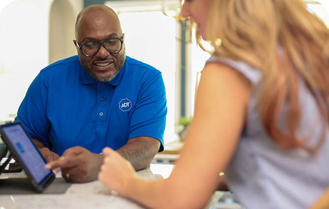 Woman self installing an ADT indoor camera on a shelf in her home