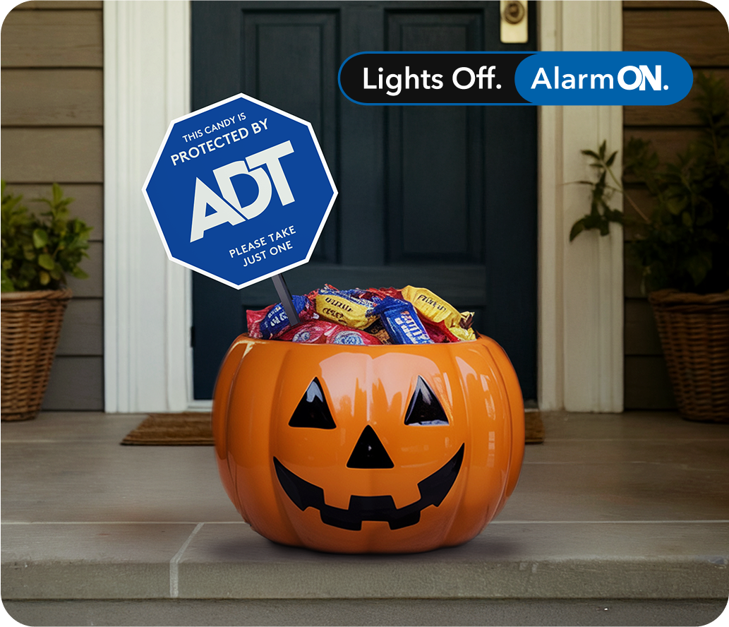 Halloween candy bucket on doorstep with special holiday ADT yard sign reading 