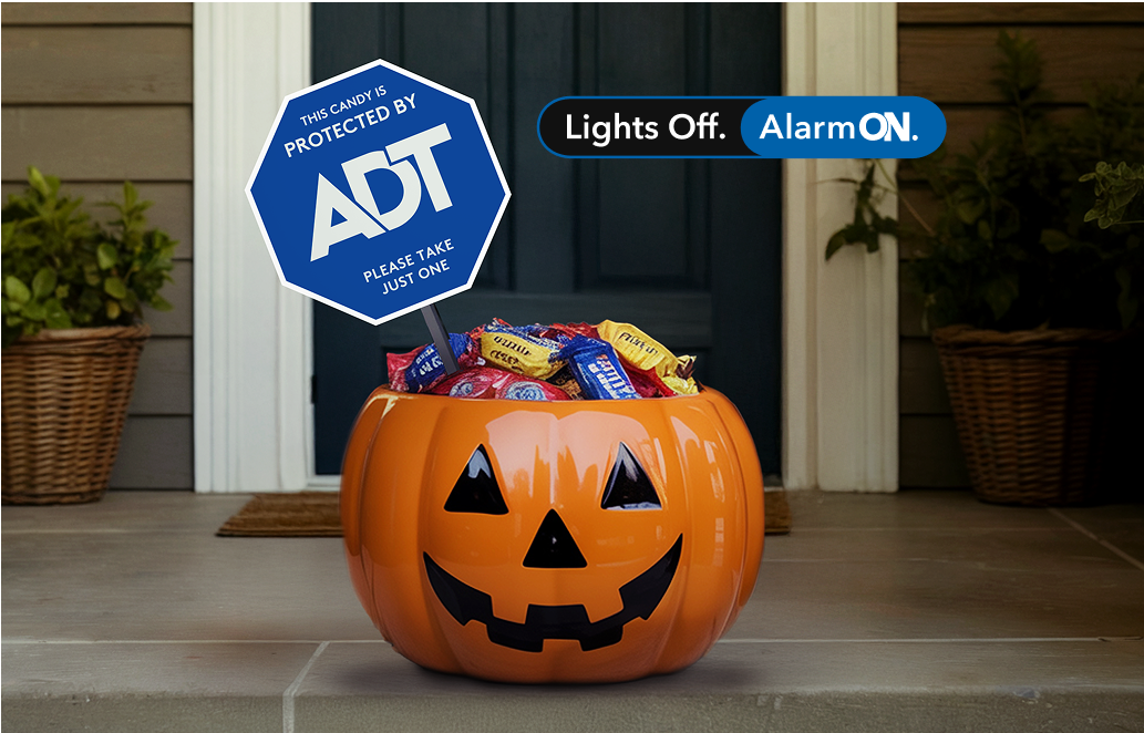 Halloween candy bucket on doorstep with special holiday ADT yard sign reading 