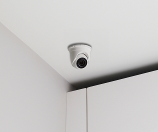 A ceiling-mounted ADT turret camera inside a commercial space, monitoring the area for safety and security. ADT installer and customer in her home