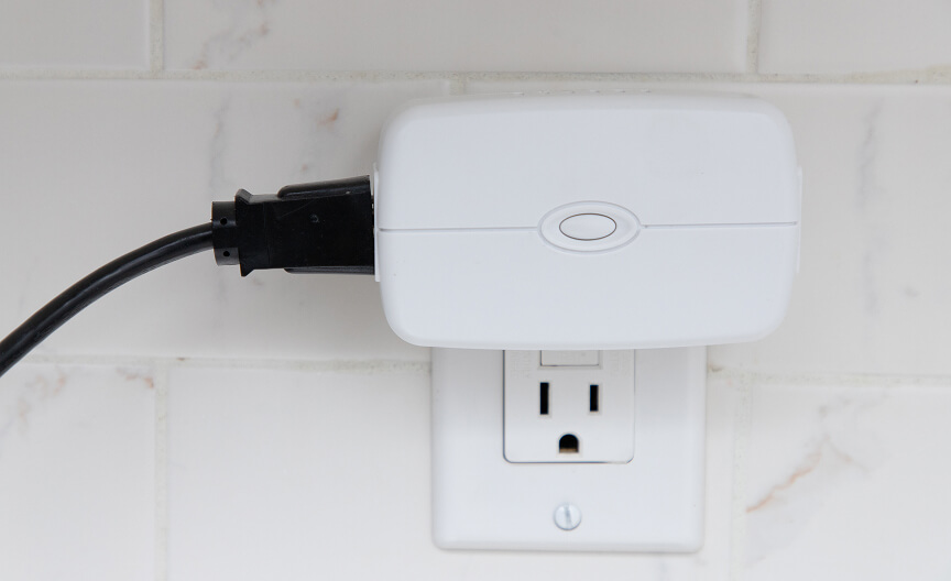 An ADT smart plug inserted into a wall outlet, providing remote control and energy management for connected devices.
