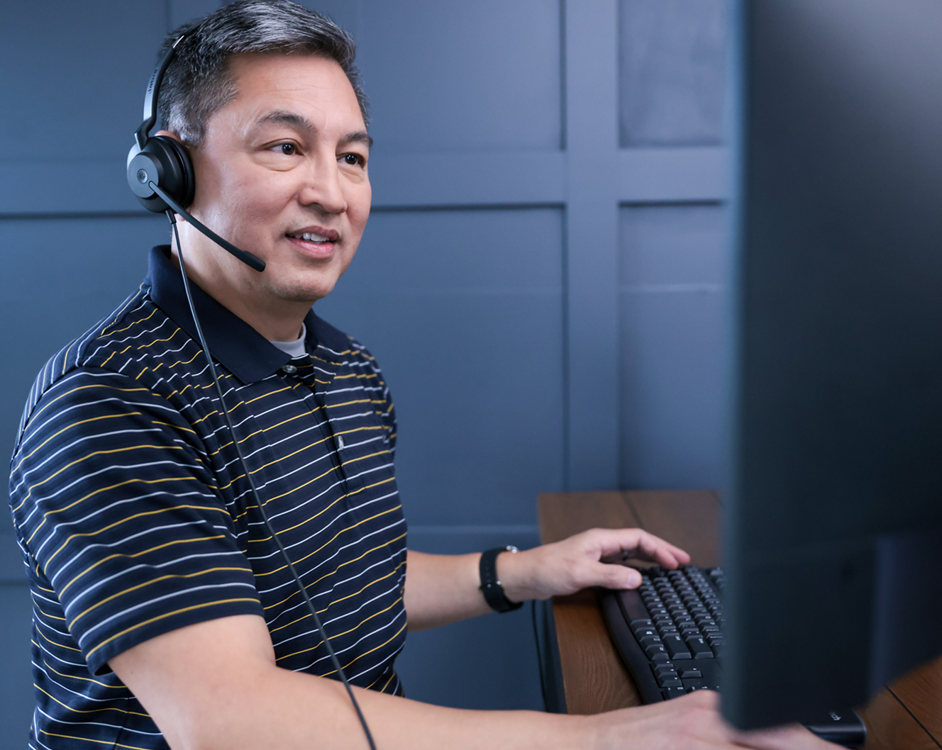ADT customer service rep typing on his computer and troubleshooting with a customer on his headset 