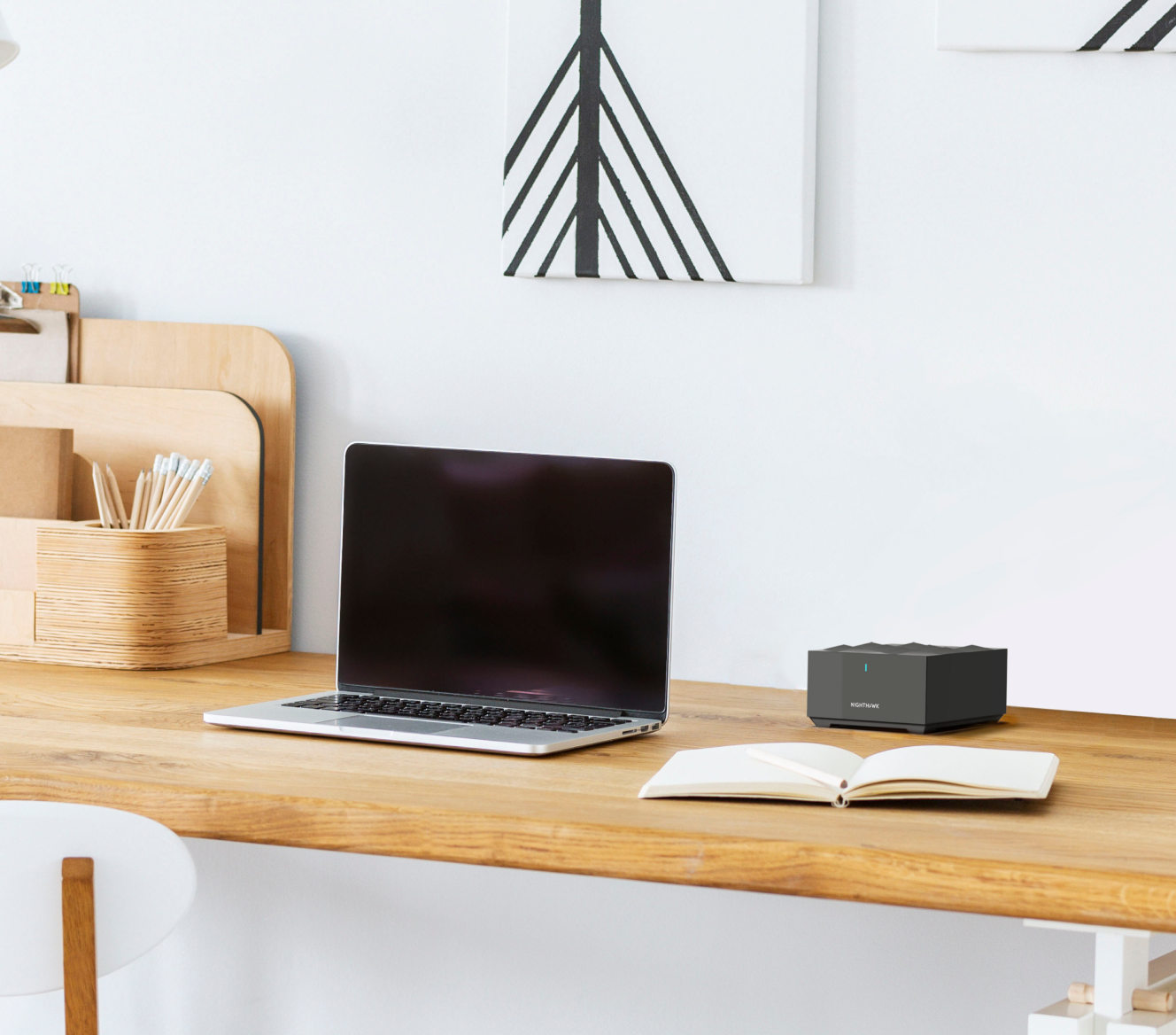 Netgear Mesh WiFi on a wooden desk next to a laptop and notebook Netgear Mesh WiFi on a wooden desk next to a laptop and notebook